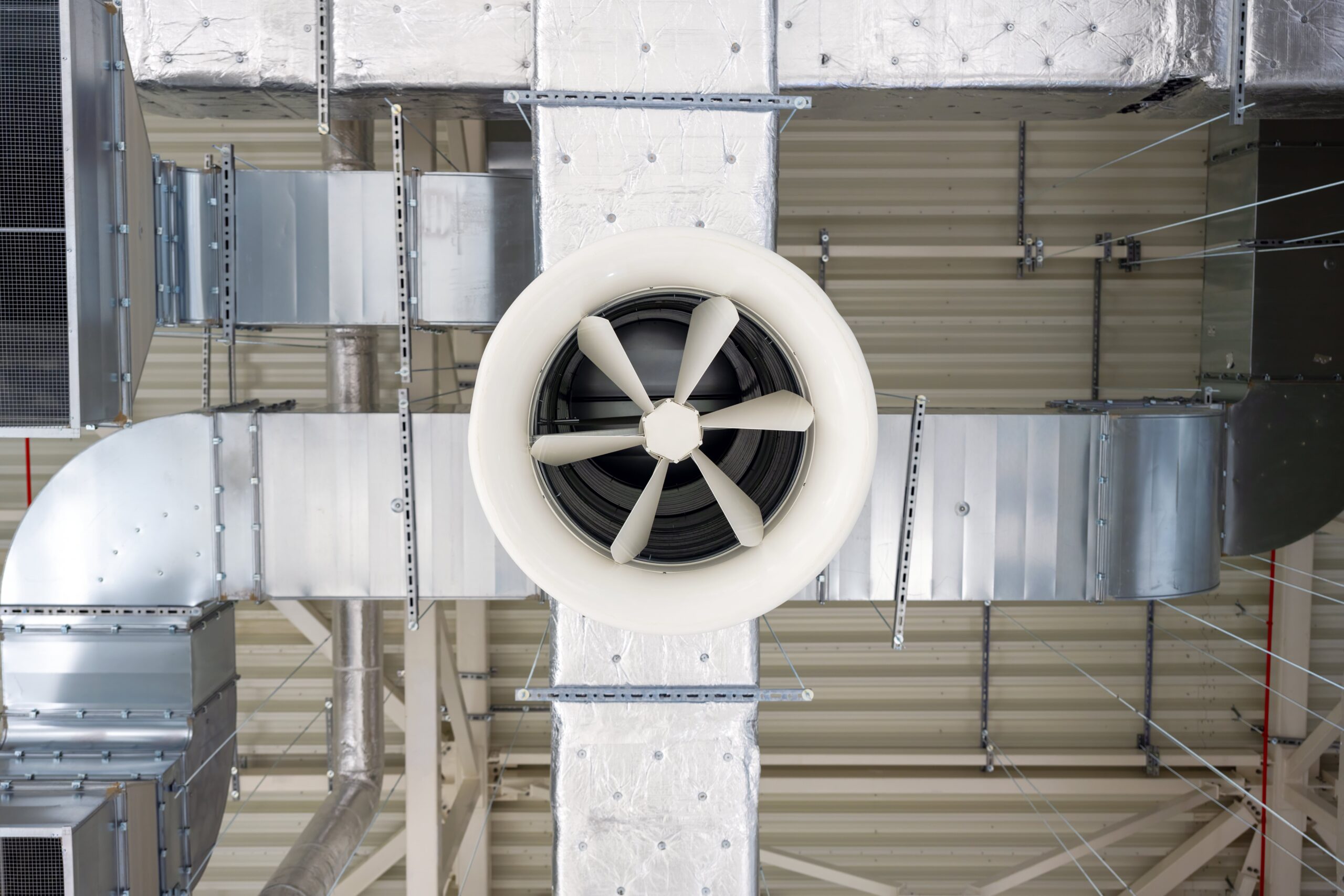 Luftkanalsystem mit Ventilator in moderner Industrieumgebung. Fokus auf Klimaanlagen und Energieeffizienz. Climate Energy.