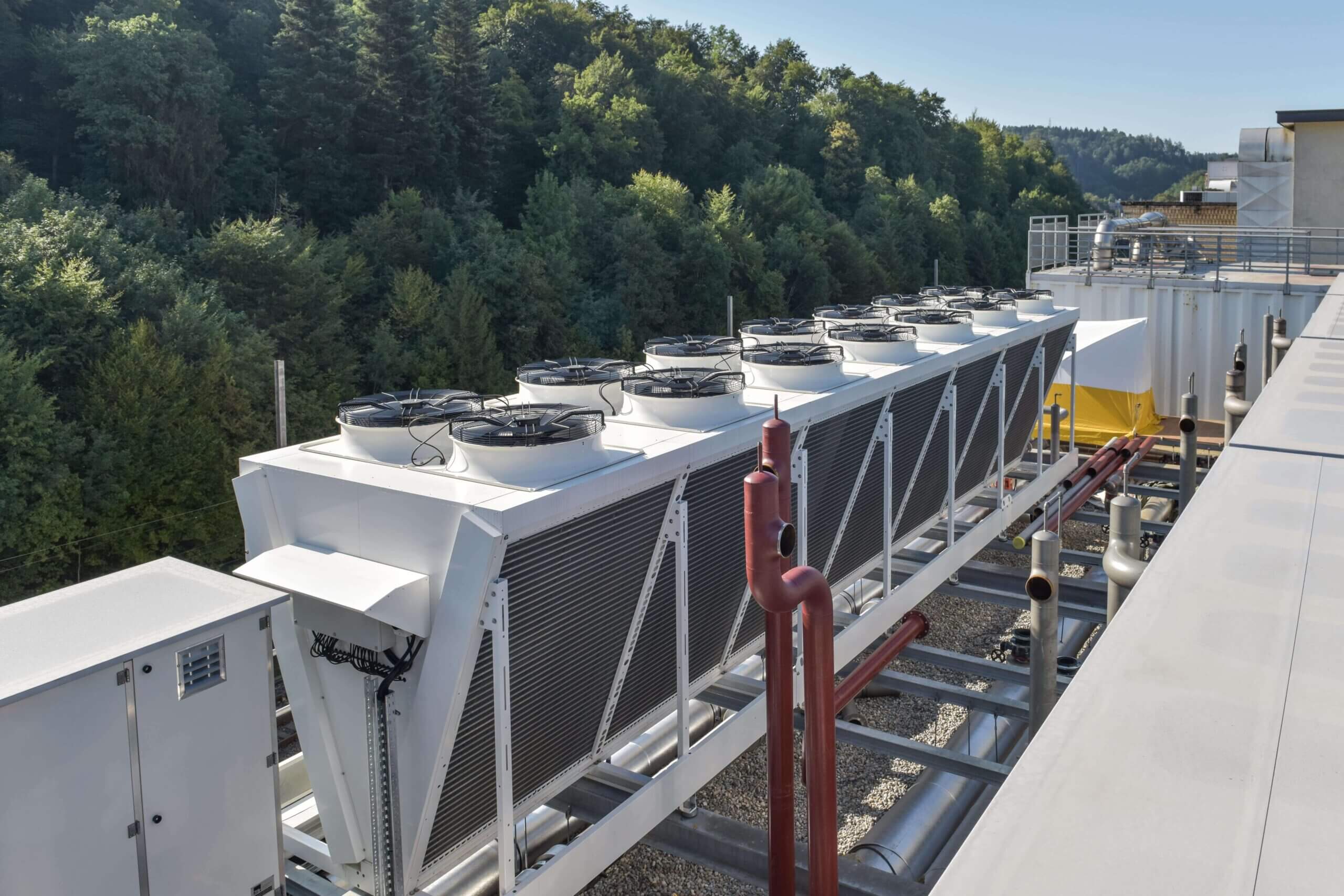 Klimaanlage auf dem Dach mit mehreren K&uuml;hlt&uuml;rmen, umgeben von Wald. Klimaanlage Energie.