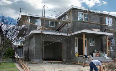 Neubau eines Hauses mit Ger&uuml;st, Arbeiter bei der Fertigstellung, Fokus auf nachhaltige Bauweise. Climate Energy.