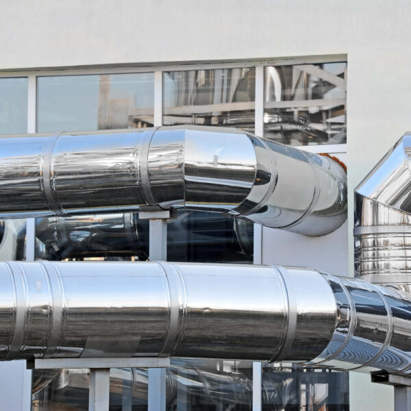 Gl&auml;nzende Rohrleitungen an einem Geb&auml;ude, Symbol f&uuml;r moderne Energietechnologie. Climate Energy.